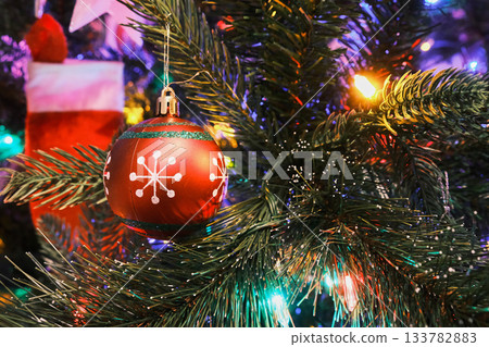 Glass ball toy on a Christmas tree with colorful lights 133782883