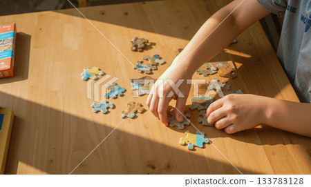 overhead view of a table where a child is putting together a puzzle, copy space dedicated to fine motor skills and child development 133783128