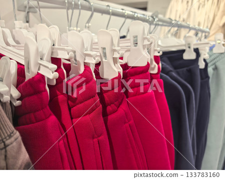 Colorful collection of clothing hanging in a stylish retail shop display Colorful collection of clothing hanging in a stylish retail shop display 133783160