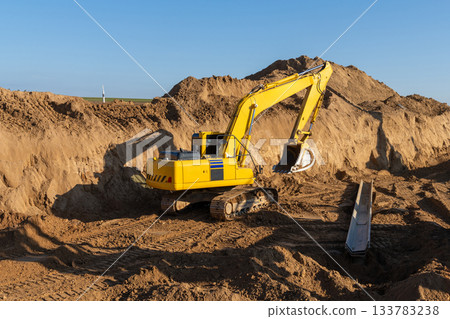 A large yellow excavator works on a construction site A large yellow excavator works on a construction site 133783238