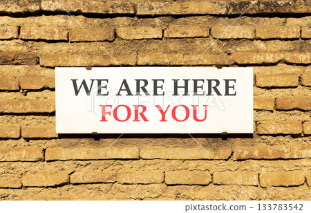 Support, help and we are here for you symbol. Concept words We are here for you on beautiful white marble sign plate. Beautiful brick wall background. Business we are here for you concept. Copy space. 133783542