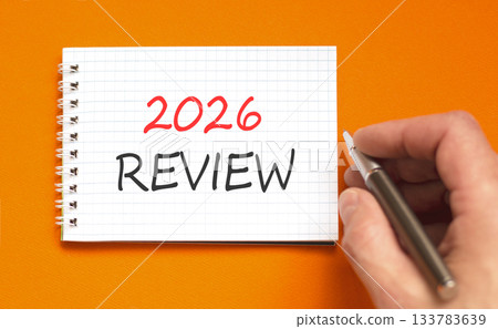 2026 Review symbol. Concept words 2026 Review on beautiful white note. Beautiful orange paper background. Businessman's hand with pen. Business and 2026 review concept. Copy space. 133783639