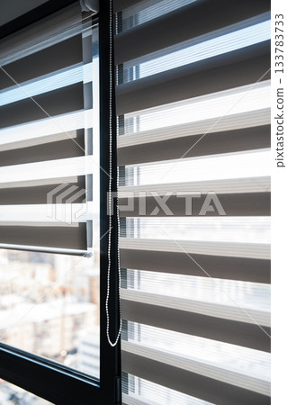 Zebra roller blinds on tall window with sunlight and urban city view background Zebra roller blinds on tall window with sunlight and urban city view background 133783733