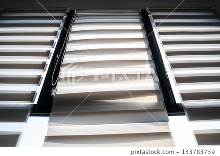 Modern double zebra blinds covering panoramic windows with bright natural light 133783739
