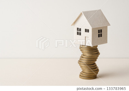 A paper house standing on a tower of coins. Space for text. A paper house standing on a tower of coins. Space for text. 133783965