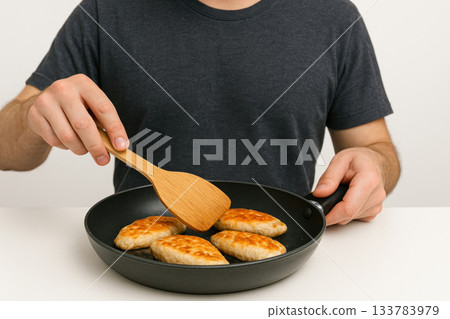 A man is frying cutlets in a pan in the kitchen. A man is frying cutlets in a pan in the kitchen. 133783979