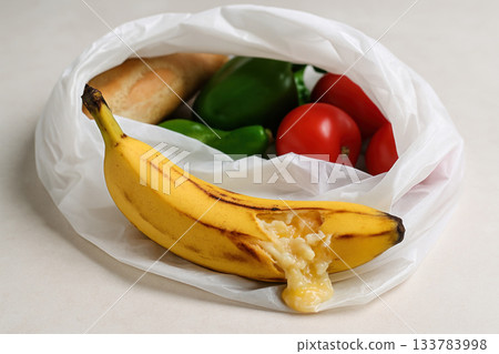 A burst banana lying among the vegetables in a bag. A burst banana lying among the vegetables in a bag. 133783998