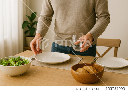 Man setting the table for a homemade dinner in a cozy kitchen. 133784093