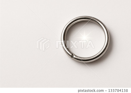 A metal ring with a shiny reflection on a white background. Space for text. 133784138