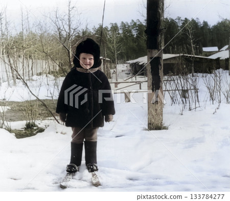 A vintage portrait of a little boy in a fur coat and hat learning to cross-country ski. Retro photo from the 1970s. 133784277