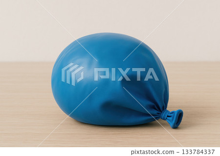 A slightly lowered blue balloon on a wooden surface. 133784337