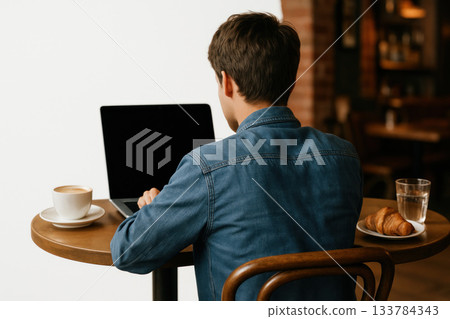 A young man is working on a laptop in a cafe. Space for text. A young man is working on a laptop in a cafe. Space for text. 133784343
