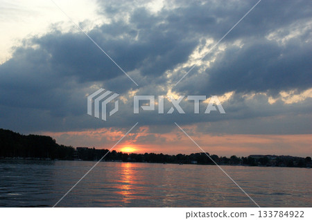 lake Mazury Poland sunset on the lake with orange sky cloudy clouds red and purple sun lake Mazury Poland sunset on the lake with orange sky cloudy clouds red and purple sun 133784922