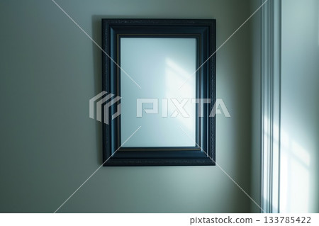 empty black picture frame on green wall with soft window light 133785422