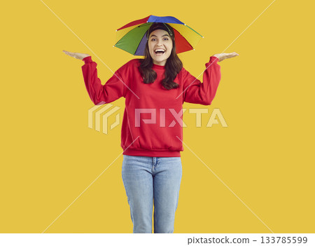 Portrait of happy woman in rainbow hat umbrella spreading her palms to sides Portrait of happy woman in rainbow hat umbrella spreading her palms to sides 133785599