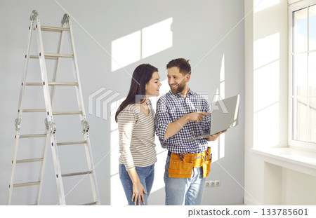 Repairman with tools and laptop discussing repairs in the house with young woman 133785601