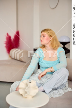refined woman with serene expression, graceful blonde woman seated with refined aesthetic ambiance 133785833