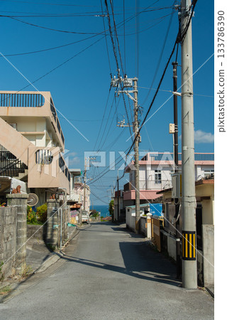 A straight road in a back alley in a town with good weather and a view of the emerald green sea in the distance A straight road in a back alley in a town with good weather and a view of the emerald green sea in the distance 133786390