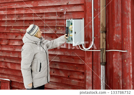 Meter imaging frames rural resident with brown hair using smartphone opposite snowy wall capturing meter photo amid winter weather. 133786732