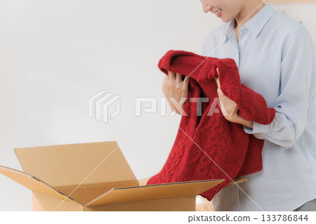 女人從盒子裡拿出一件毛衣 133786844