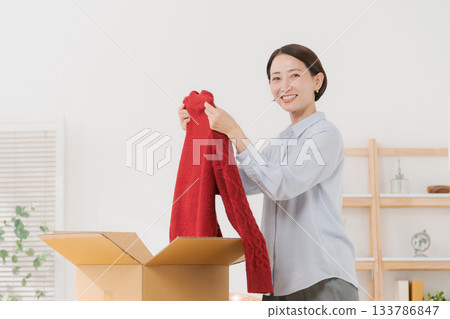 女人從盒子裡拿出一件毛衣 133786847