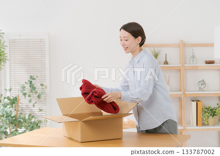 一位女士正在把衣服裝箱。 一位女士正在把衣服裝箱。 133787002