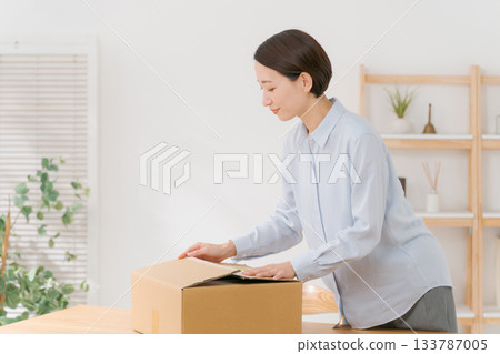 一位女士正在把衣服裝箱。 一位女士正在把衣服裝箱。 133787005