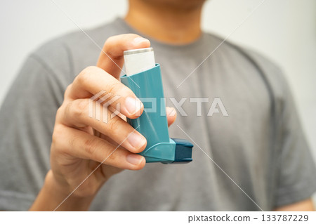 Asthma and chronic obstructive pulmonary disease COPD, Asian young man using metered dose inhaler MDI. 133787229