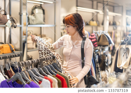 Young woman chooses sweatshirt in store 133787319