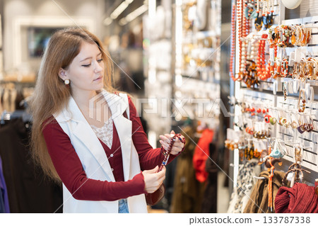 Young woman chooses beads in accessories store Young woman chooses beads in accessories store 133787338