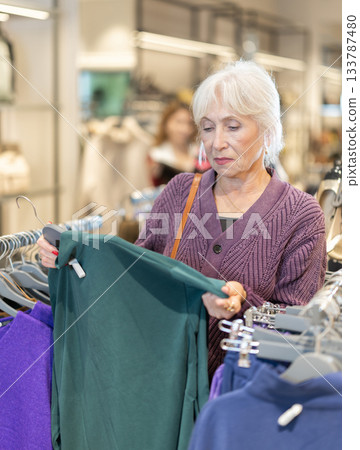 Positive mature woman choosing pullover in clothing store Positive mature woman choosing pullover in clothing store 133787480