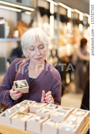 Attentive mature woman choosing wrist watch in accessories store 133787505