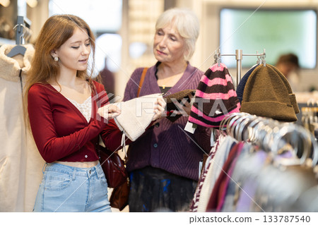 Mature woman helping a young woman choose a hat 133787540