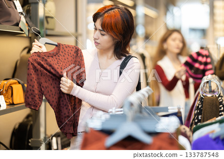 Young Asian woman choosing a wool sweater in a store Young Asian woman choosing a wool sweater in a store 133787548