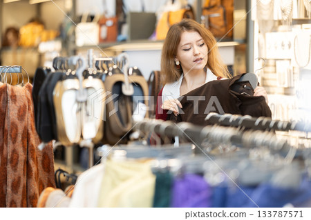 Young woman chooses coat in clothing store 133787571