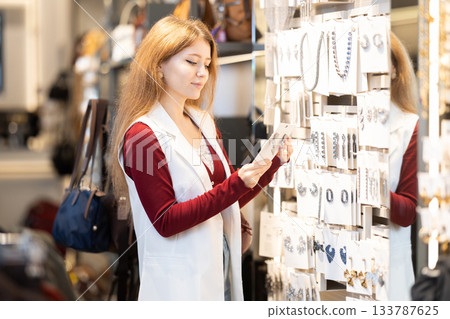 Young woman search and choose earrings Young woman search and choose earrings 133787625
