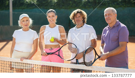 Group of friends stand near the net on a tennis court Group of friends stand near the net on a tennis court 133787777