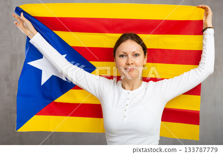 Happy smiling woman proudly displaying catalan flag Happy smiling woman proudly displaying catalan flag 133787779