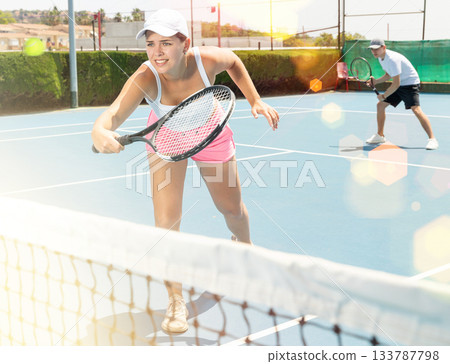 Young woman playing tennis with her teammate in court Young woman playing tennis with her teammate in court 133787798