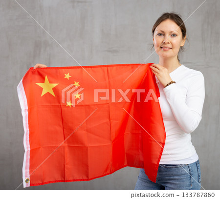 Happy young woman holding flag of China against unicoloured background 133787860