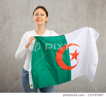 Happy woman posing with national flag of Algeria in studio Happy woman posing with national flag of Algeria in studio 133787867