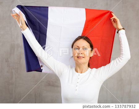 Happy young woman holding flag of France against unicoloured background 133787932