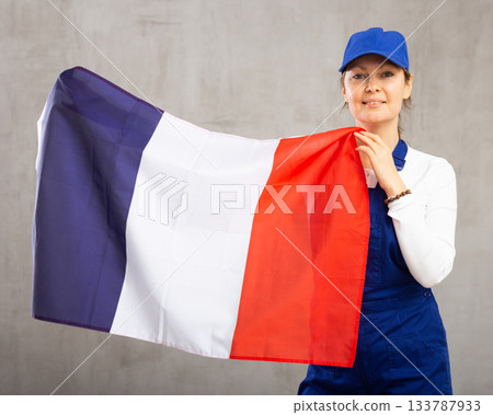 Smiling adult woman in uniform holding France flag Smiling adult woman in uniform holding France flag 133787933