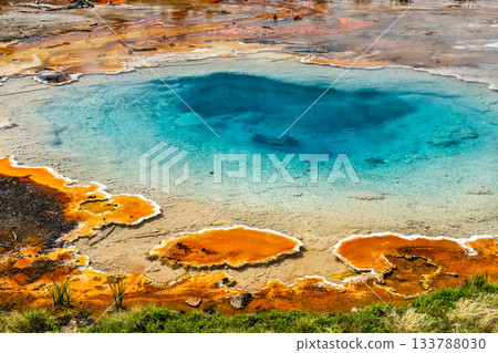 Colorful Silex Spring bubbles with hot blue water in Yellowstone National Park Wyoming. Geothermal feature displays vibrant orange bacterial mats contrasting with deep turquoise pool on sunny day Colorful Silex Spring bubbles with hot blue water in Yellowstone National Park Wyoming. Geothermal feature displays vibrant orange bacterial mats contrasting with deep turquoise pool on sunny day 133788030