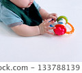 A crawling baby looking at a toy on a baby mat 133788139