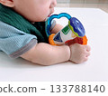 Crawling baby sucking on a toy on a baby mat 133788140