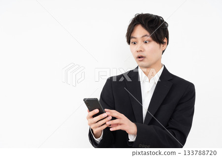 A young businessman operating a smartphone on a white background A young businessman operating a smartphone on a white background 133788720