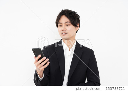 A young businessman operating a smartphone on a white background A young businessman operating a smartphone on a white background 133788721