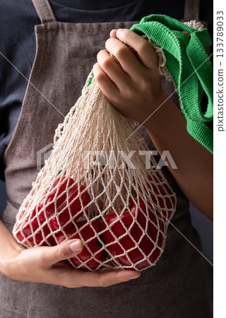 Fresh red bell pepper or sweet pepper in mesh bag with hand Fresh red bell pepper or sweet pepper in mesh bag with hand 133789033