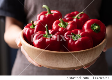 Fresh red bell pepper or sweet pepper in wooden bowl holding by woman hand Fresh red bell pepper or sweet pepper in wooden bowl holding by woman hand 133789035